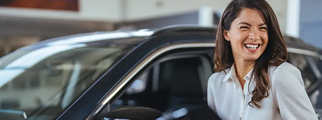 A woman standing next to a car and smiling.