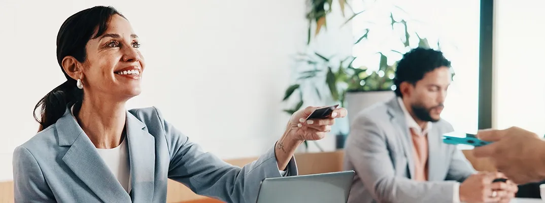 A woman at a desk handing a customer their debit card.