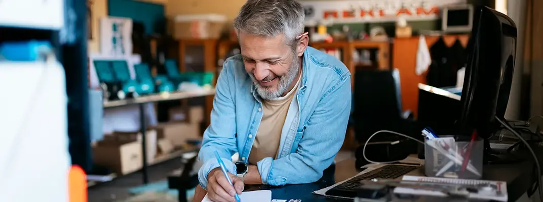 A man at a business writing on a notepad.