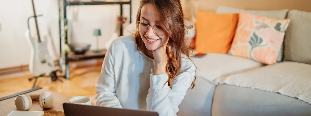 A woman smiling in front of her laptop.