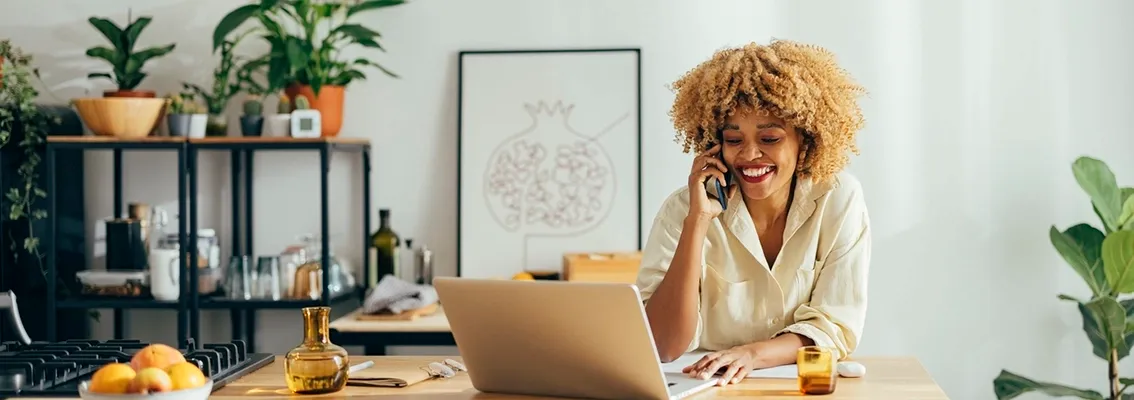 A woman on the phone looking at her laptop