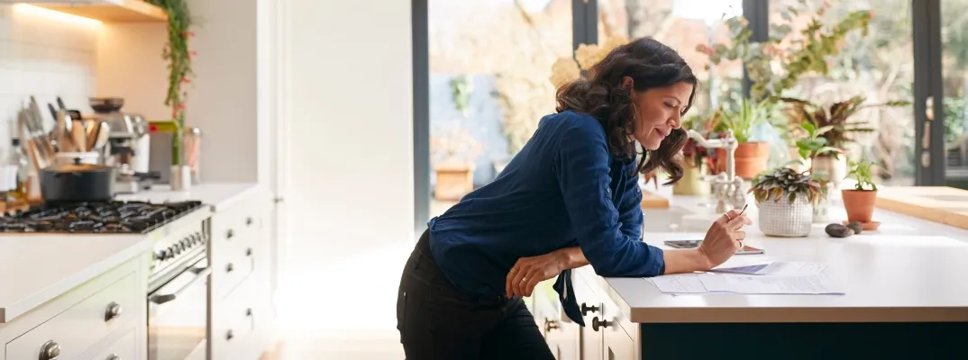 A woman leaning on a counter reading a document