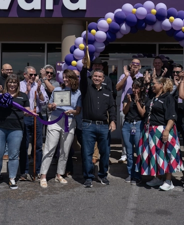 Ivan Olvera cuts the ribbon in front of the South Valley branch during its grand opening while others around him applaud and cheer