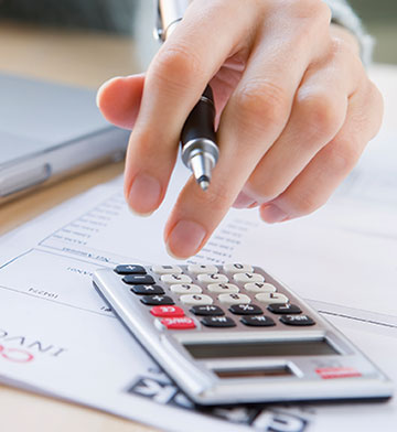 Hand holding pen and working a calculator