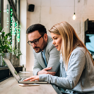 Young couple looking at computer screen and smiling.