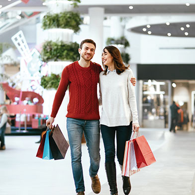 Couple in sweaters holding shopping bags in mall