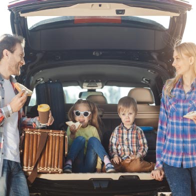 Family eating lunch outside of the trunk of their vehicle