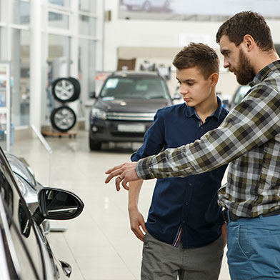 Dad and son looking at car in dealership.