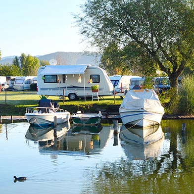 Several RVs parked near a lake with two boats.