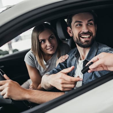 Image of couple being handed keys to their first car