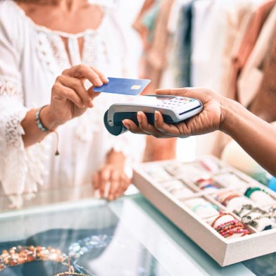 Close-up of woman using credit card to tap to pay at store