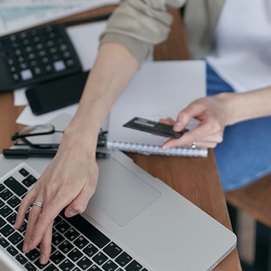 Close up of woman referencing credit card while using laptop