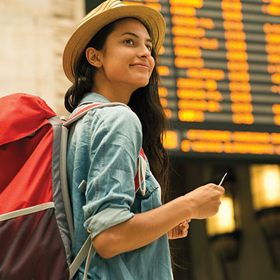 Woman at an airport, holding an airline ticket and smiling