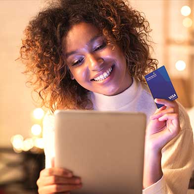 Woman holding an Sunward credit card while shopping only using her laptop