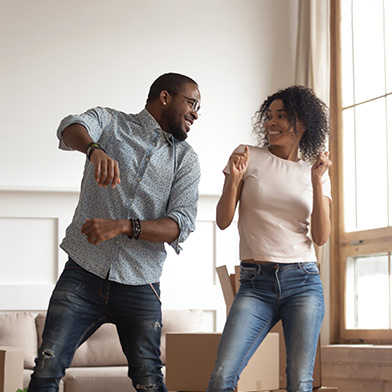 Couple dancing in living room surrounded by moving boxes