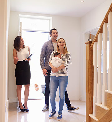 Young couple with a baby being shown a new home by a realtor.