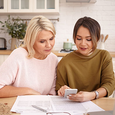 Mom and daughter sitting at kitchen table looking over finances