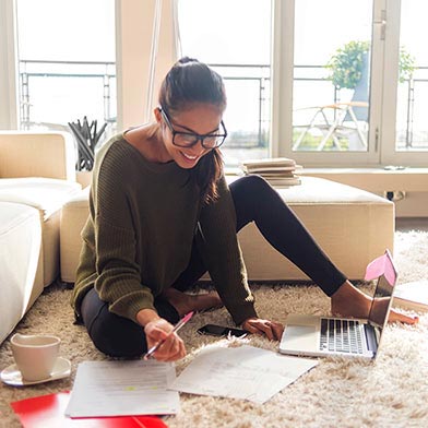 Young adult with glasses sitting on floor with financial papers