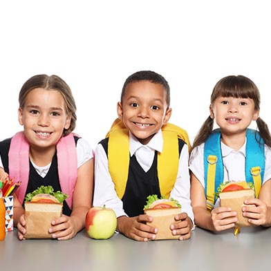 Image of school children with backpacks eating lunch