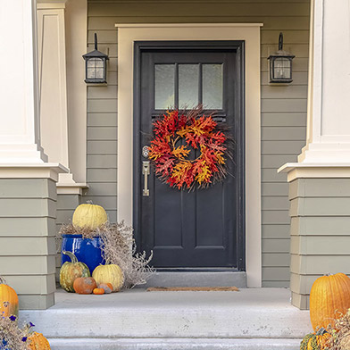 Picture of a front porch featuring pumpkins and fall decorations.