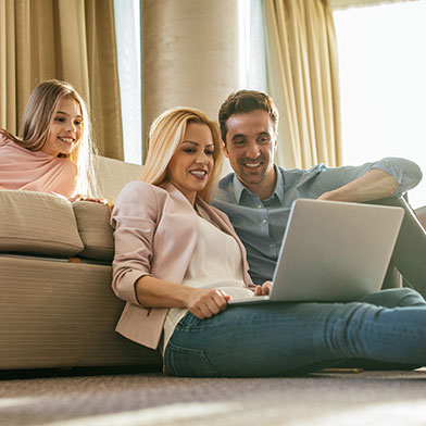 Couple and their daughter sitting in the living room and looking at tablet