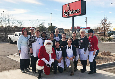 Sunward employees pose with Santa Claus in front of the Applebee's sign in Los Lunas