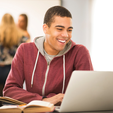 Young man who is using his laptop with book near him