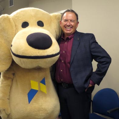 Sandy the Lab and Robert Chavez, former Sunward President and CEO, pose for a photo