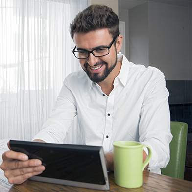 Bearded younger man looking at his tablet while seated at a table