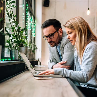 Man and woman at kitchen table staring intently at laptop computer.