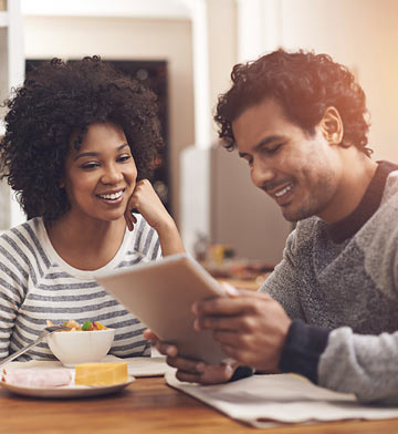 Man and woman smiling looking at tablet.