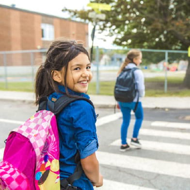 child wearing backpack outside school