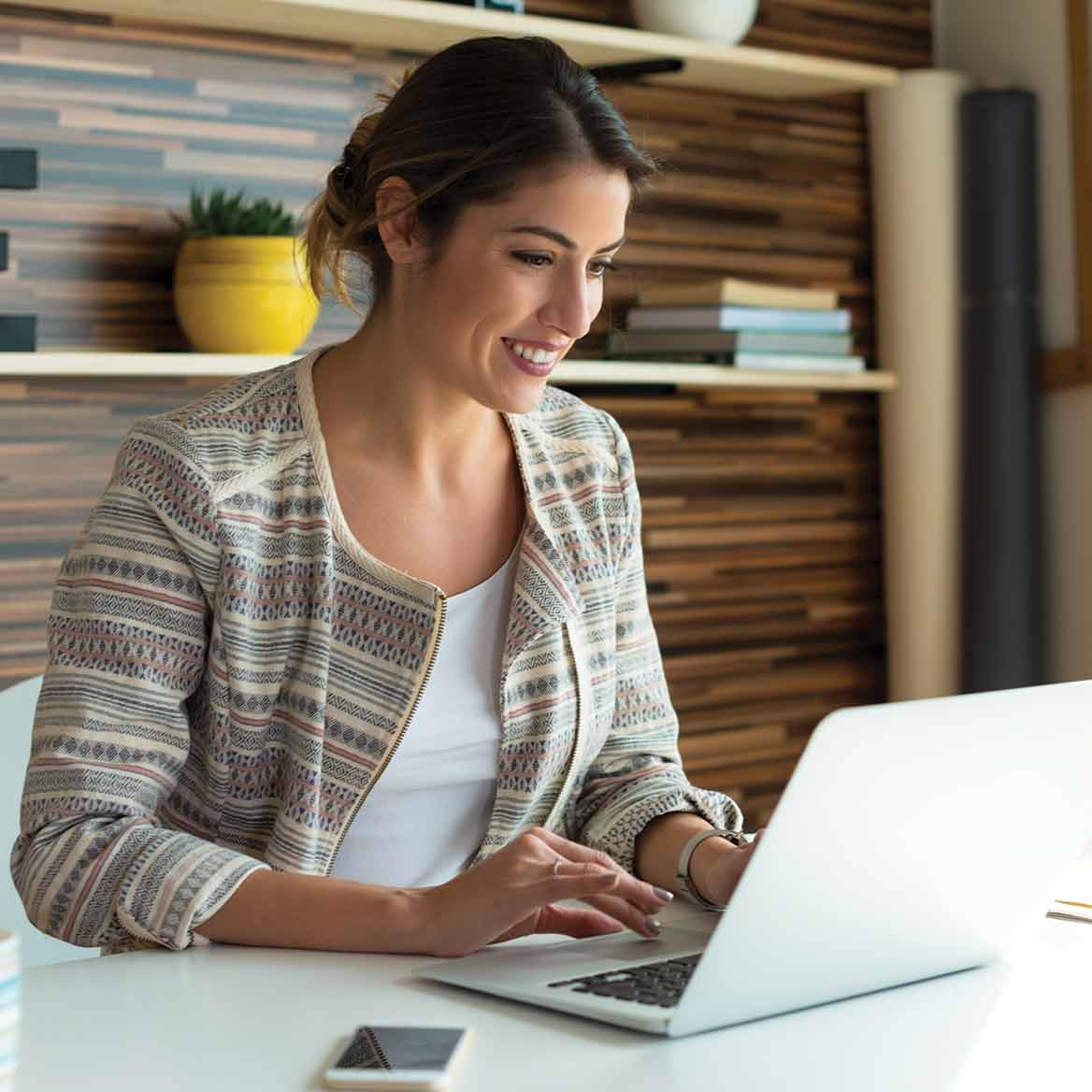 Woman smiling and looking at laptop.