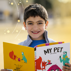Child reading a book and looking up with big happy smile