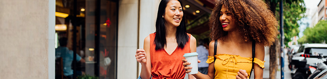 Two smiling women walking down a city street