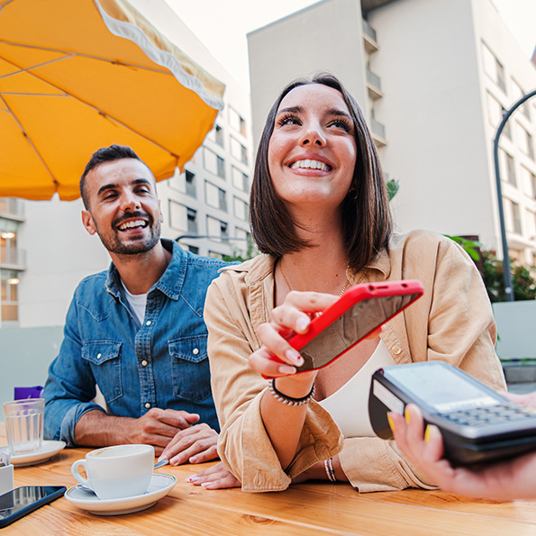 A smiling woman paying for her meal at a restaurant using her phone