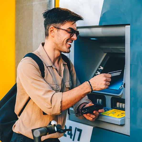 A smiling man using an ATM