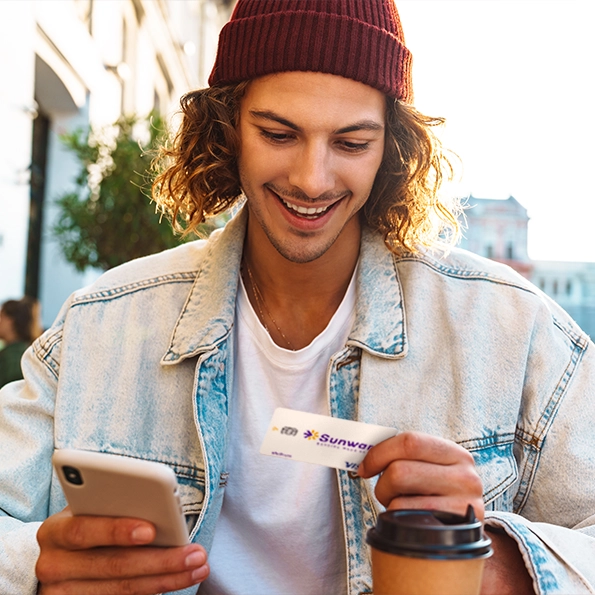 A man with a smart phone holding a Visa Platinum Rebate Credit Card