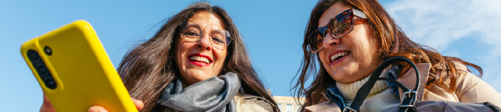 Two women, outside, looking at a cellphone