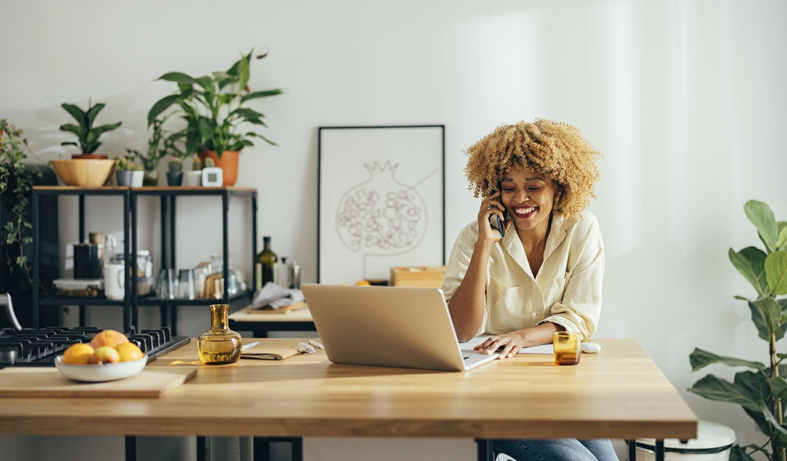 A woman on the phone looking at her laptop